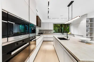 a kitchen with white cabinets and black appliances at Luxury 6-Bedroom Villa stunning 3-story estate in Golden Beach