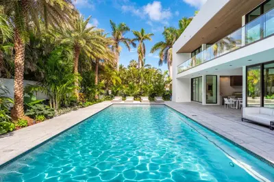 a swimming pool in the backyard of a house with palm trees at Luxury 6-Bedroom Villa stunning 3-story estate in Golden Beach