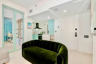 a green couch in a living room with a kitchen at 2-Min to Beach, Upscale Enclave in Miami Beach
