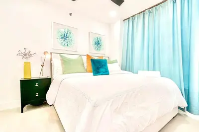 a bedroom with a large white bed with blue curtains at 2-Min to Beach, Upscale Enclave in Miami Beach