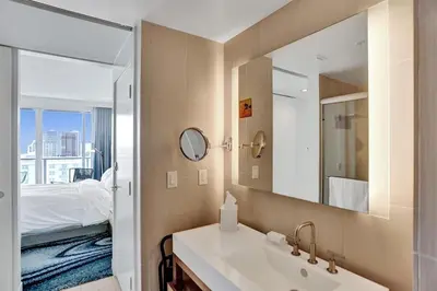 a bathroom with a sink and a bed and a mirror at Luxury Beachfront Two Bedroom Condo - W Residences in Fort Lauderdale