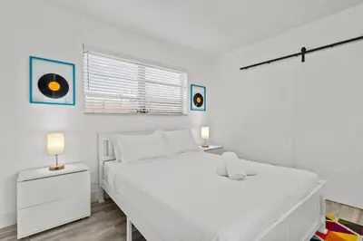 a white bedroom with a large white bed and two lamps at Pool, golf & 4 mi. from the beach & The Hard Rock in Hollywood