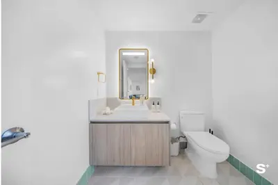 a bathroom with a sink and a toilet and a mirror at City Luxe Retreat Modern 2-BD with Water Views in Miami
