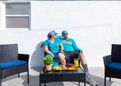 a man and woman sitting on a chair with a table with fruit at HavanaDolphinsluxury 2PPL TopLocation Parking Pets in Hollywood Ridge Farms