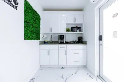 a kitchen with white cabinets and a green wall at HavanaDolphinsluxury 2PPL TopLocation Parking Pets in Hollywood Ridge Farms