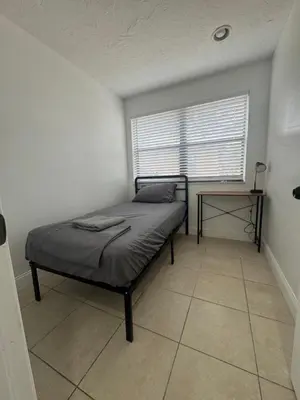 a small bedroom with a bed and a window at Pacifica Fort Lauderdale Airport in Dania Beach
