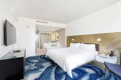 a bedroom with a large white bed and a bathroom at 16th Floor Luxury 2 Bedroom - Ocean Views & Luxury in Fort Lauderdale