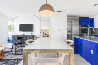 a kitchen with a white table and blue cabinets at W Residences 2 Bed Unit - Beachfront and Luxe Stay in Fort Lauderdale