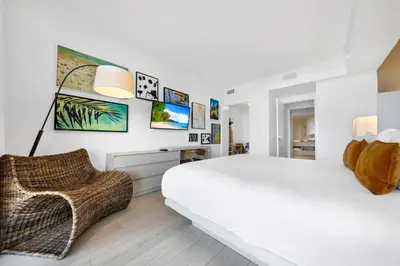 a white bedroom with a large bed and a chair at High-End Apartment in a Luxury Resort with Gorgeous Amenities in Hollywood