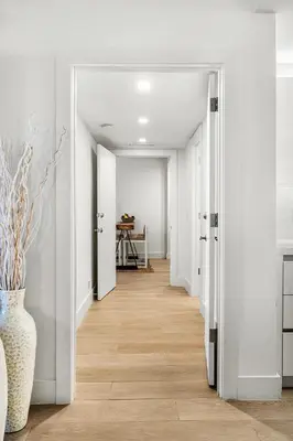 a hallway with white walls and wood floors at 2 Bedroom Private Residence at Roney Palace -11289 in Miami Beach