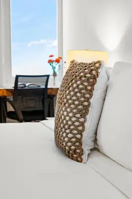 a pillow on a bed with a table and a window at 2 Bedroom Private Residence at Roney Palace -11289 in Miami Beach