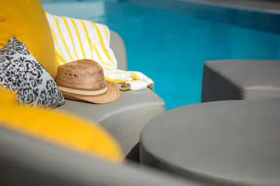 a straw hat sitting on a couch next to a pool at Hyatt Centric South Beach Miami in Miami Beach