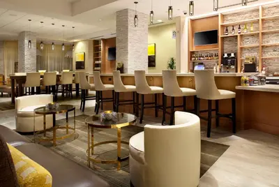 a restaurant with a bar with stools and tables at Hyatt Place Miami Airport East in Miami