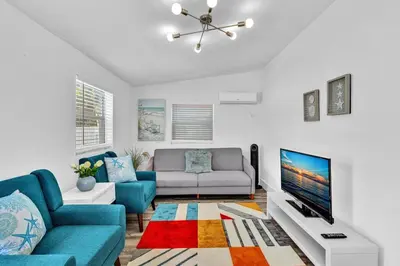 a living room with a blue couch and a tv at Dream Hollywood Beach Retreat With Jacuzzi and Fire Pit in Dania Beach
