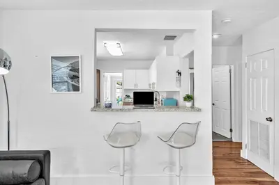 a white kitchen with two chairs and a counter at Dream Hollywood Beach Retreat With Jacuzzi and Fire Pit in Dania Beach