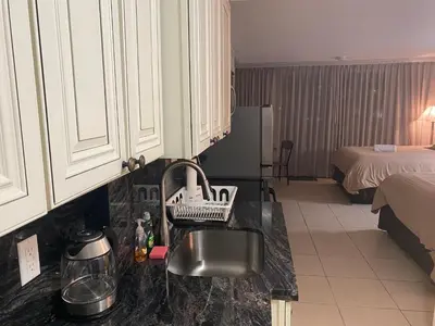a kitchen with a sink and a room with a bed at All you need around you in Sunny Isles Beach