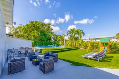 a patio with furniture and a backyard with a pool at The Glow House w Cinema, Disco, Pool, BBQ, 9 beds in Ives Estates