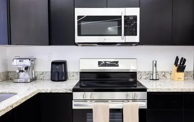 a kitchen with a stove and a microwave at The Glow House w Cinema, Disco, Pool, BBQ, 9 beds in Ives Estates