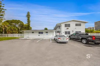 a white house with a truck parked in a parking lot at Modern Studio in Miami Gym, BBQ, Free Parking in Miami