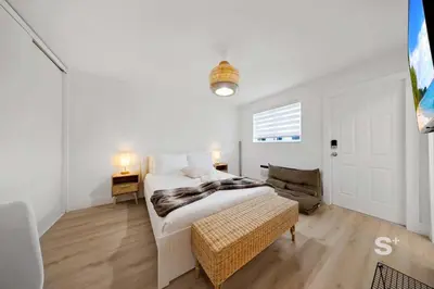 a white bedroom with a bed and a chair at Modern Studio in Miami Gym, BBQ, Free Parking in Miami