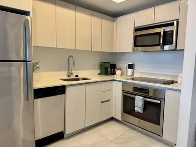 a kitchen with white cabinets and stainless steel appliances at 1BR on Miami Beach with Beach Service & Near Mall in Hallandale Beach