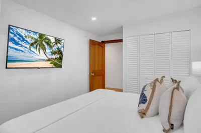 a white bedroom with a white bed with a painting on the wall at Grand historic Residence Walk to beach Heated Pool Outdoor kitchen Hibiscus Key Residences in Fort Lauderdale