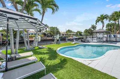 a swimming pool with chaise lounge chairs next to a yard at Waterfront Bungalow Heated Pool Pineapple Key in Fort Lauderdale