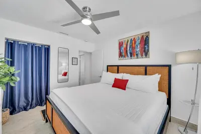 a bedroom with a large white bed with a red pillow at Waterfront Bungalow Heated Pool Pineapple Key in Fort Lauderdale