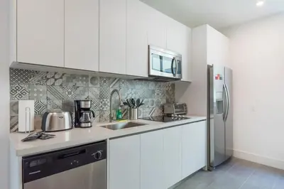 a kitchen with white cabinets and a stainless steel refrigerator at Apto Moderno a 5min da Praia em South Beach in Miami Beach