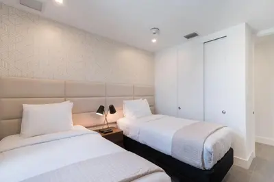two beds in a bedroom with white walls at Apto Moderno a 5min da Praia em South Beach in Miami Beach