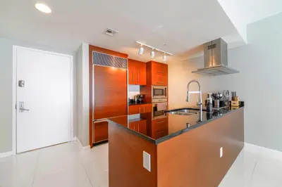 a kitchen with wooden cabinets and a sink at Panoramic City Views From 45th Floor Brickell Condo in Miami