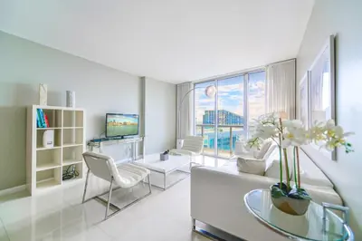 a white living room with a couch and a tv at Panoramic City Views From 45th Floor Brickell Condo in Miami