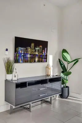 a black entertainment center in a living room with plants at Luxury 2BR with City Views on Biscayne Blvd in Miami