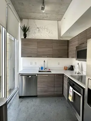 a kitchen with wooden cabinets and stainless steel appliances at Pop Art Sunlit Apartment Prime Miami Pool Free Parking in Miami