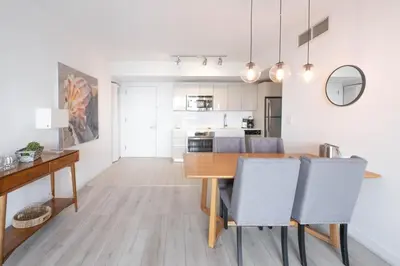 a kitchen and dining room with a wooden table and chairs at Trendy Miami Apartment Walk to the Beach in Hallandale Beach