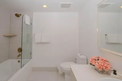 a white bathroom with a toilet and a sink at Amazing 2B 2B Luxury Beach Apmt in Hallandale Beach