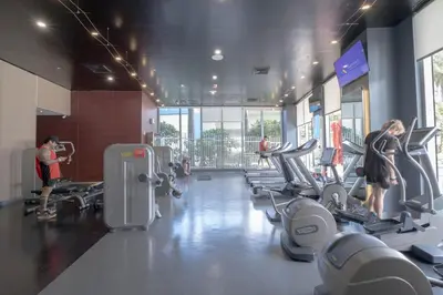 a gym with several people exercising on tread machines at Amazing 2B 2B Luxury Beach Apmt in Hallandale Beach