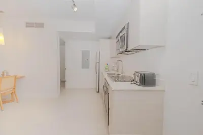 a white kitchen with a sink and a refrigerator at Ocean views pool gym and more in Hallandale Beach