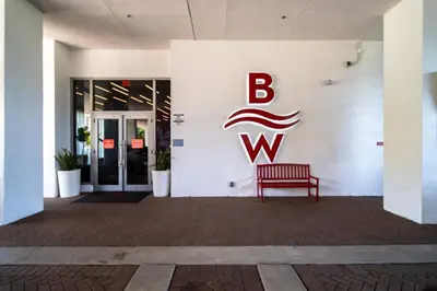 a red bench in front of a building with a bwk sign at Perfect getaway beach pool and gym 2B 2B in Hallandale Beach