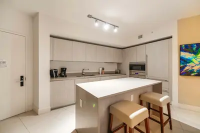 a kitchen with a counter and stools in it at Stylish Condo Steps From the Beach! in Hollywood