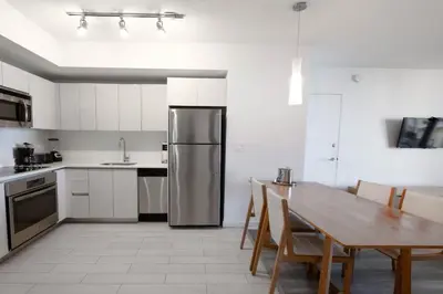 a kitchen with a table and a stainless steel refrigerator at 2B 2B Beachfront Pool Gym and Restaurant 2004 in Hallandale Beach
