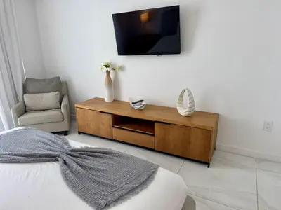 a bedroom with a tv on the wall and a chair at Hallandale Beach Apmt 1B 1B Beach & Pool Service in Hallandale Beach