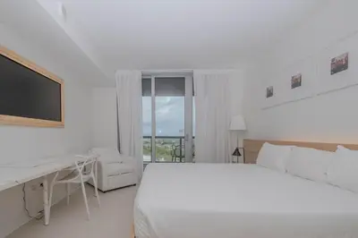 a white bedroom with a bed and a desk at Enjoy Miami 2B 2B pool beach and Aventura Mall in Hallandale Beach