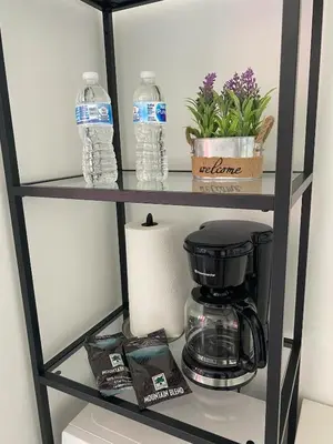 a shelf with a coffee maker and water bottles at Beach, pool, and Gym 2B 2B Near Gulfstream & Mall in Hallandale Beach