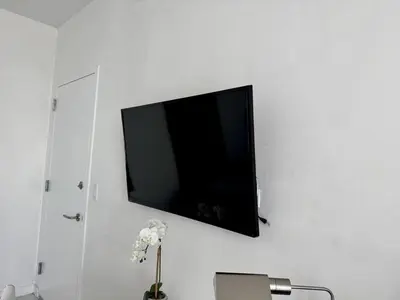a flat screen tv hanging on a white wall at Getaway in Miami 2B 2B beachfront near Aventura 3003 in Hallandale Beach