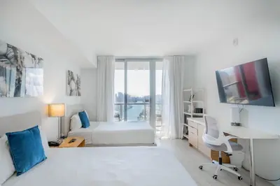 a white bedroom with a bed and a desk with a computer at 2B 2B Beautiful Apt in Hallandale Beach with Beach Service 2605 in Hallandale Beach