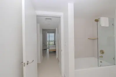 a white bathroom with a walk in shower and a glass door at Miami Apt with Gym Beach Service Pool on the water 2607 in Hallandale Beach