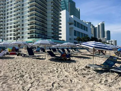 a group of chairs and umbrellas on a beach at Beach Apt with Full kitchen and King size bed in Hallandale Beach