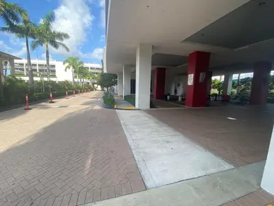an empty sidewalk next to a building with palm trees at Beach Apt with Full kitchen and King size bed in Hallandale Beach