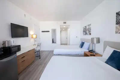 a hotel room with two beds and a flat screen tv at Relax in Miami 2B 2B Beach and Pool with Drinks in Hallandale Beach